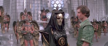 Movie still from “Flash Gordon” (1980), directed by Mike Hodges – A person in a costume in front of a group of people; Medium shot, Low angle