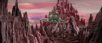 Movie still from “Flash Gordon” (1980), directed by Mike Hodges – An airplane flying over a mountain with a castle in the background; Extreme Wide shot, High angle