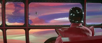 Movie still from “Flash Gordon” (1980), directed by Mike Hodges – A view of a sky from inside a bus window; Extreme Wide shot, Over the shoulder angle