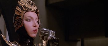 Movie still from “Flash Gordon” (1980), directed by Mike Hodges – A woman wearing a helmet is holding a microphone; Close Up shot, Low angle