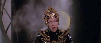 Movie still from “Flash Gordon” (1980), directed by Mike Hodges – A woman in a black and gold outfit and a gold crown; Close Up shot, Low angle