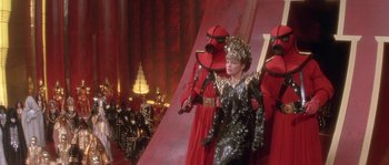 Movie still from “Flash Gordon” (1980), directed by Mike Hodges – A group of people dressed up in costumes; Wide shot, Over the shoulder angle