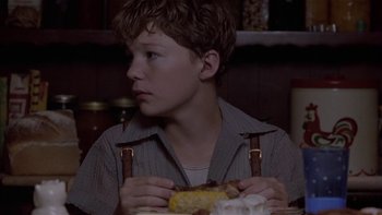 Movie still from “Flesh and Bone” (1993), directed by Steve Kloves – A boy sitting at a dinner table eating a sandwich; Close Up shot, Over the shoulder angle