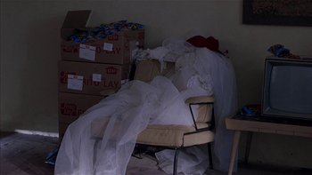 Movie still from “Flesh and Bone” (1993), directed by Steve Kloves – A pile of wedding dresses sitting on top of a chair; Wide shot, High angle