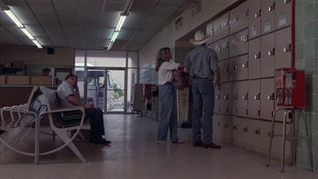 Movie still from “Flesh and Bone” (1993), directed by Steve Kloves – A man and a woman are standing in front of a row of lockers; Wide shot, High angle