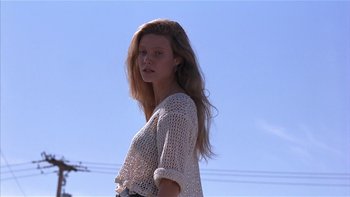 Movie still from “Flesh and Bone” (1993), directed by Steve Kloves – A beautiful young lady standing in front of power lines; Medium shot, Low angle