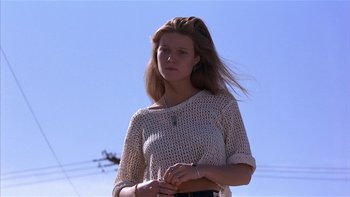 Movie still from “Flesh and Bone” (1993), directed by Steve Kloves – A woman standing in front of power lines and a blue sky; Medium shot, Low angle
