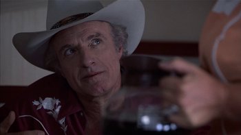 Movie still from “Flesh and Bone” (1993), directed by Steve Kloves – A man wearing a cowboy hat holding a glass of wine; Close Up shot, Over the shoulder angle