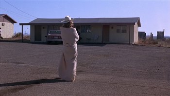 Movie still from “Flesh and Bone” (1993), directed by Steve Kloves – A woman wrapped in a blanket standing in a parking lot next to a motel; Wide shot, Over the shoulder angle