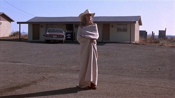 Movie still from “Flesh and Bone” (1993), directed by Steve Kloves – A woman standing in a parking lot wearing a cowboy hat; Wide shot, Low angle