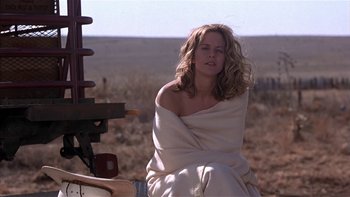 Movie still from “Flesh and Bone” (1993), directed by Steve Kloves – A woman wrapped in a blanket sitting in a field; Medium shot, Low angle