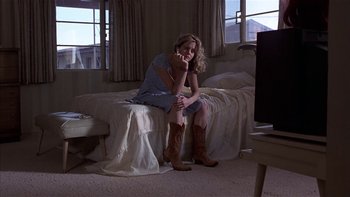 Movie still from “Flesh and Bone” (1993), directed by Steve Kloves – A woman sitting on a bed in a room; Medium shot, Low angle