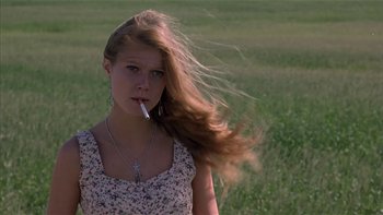 Movie still from “Flesh and Bone” (1993), directed by Steve Kloves – A woman smoking a cigarette while standing in a field; Close Up shot, Low angle