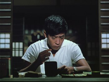 A man sitting at a table looking at a cell phone