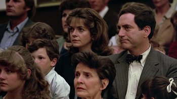 Movie still from “Footloose” (1984), directed by Herbert Ross – A group of people sitting next to each other in a room; Close Up shot, Over the shoulder angle