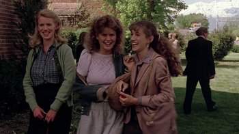 Movie still from “Footloose” (1984), directed by Herbert Ross – A couple of women standing next to each other on a field; Medium shot, Over the shoulder angle