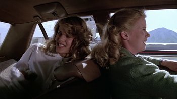 Movie still from “Footloose” (1984), directed by Herbert Ross – Two women sitting in the back seat of a car; Medium shot, Over the shoulder angle