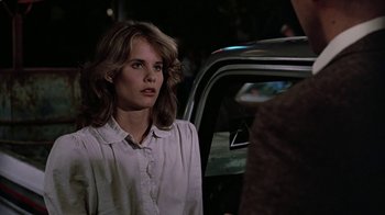 Movie still from “Footloose” (1984), directed by Herbert Ross – A woman standing in front of a parked car at night; Close Up shot, Over the shoulder angle