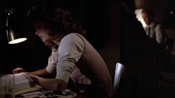 Movie still from “Footloose” (1984), directed by Herbert Ross – A woman sitting at a table with a plate in front of her; Medium shot, Low angle