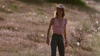Movie still from “Footloose” (1984), directed by Herbert Ross – A woman wearing a cowboy hat in the middle of a field; Medium shot, Low angle
