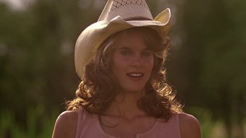 Movie still from “Footloose” (1984), directed by Herbert Ross – A woman wearing a cowboy hat and a pink dress; Close Up shot, Low angle