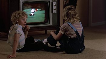 Movie still from “Footloose” (1984), directed by Herbert Ross – Two children sitting on the floor watching television; Medium shot, High angle