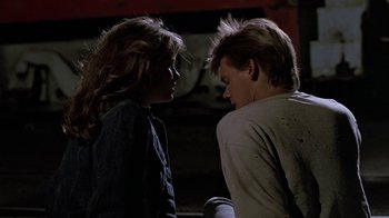 Movie still from “Footloose” (1984), directed by Herbert Ross – A young man and a young woman standing next to each other; Medium shot, Over the shoulder angle
