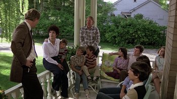 Movie still from “Footloose” (1984), directed by Herbert Ross – A group of people sitting on a porch; Wide shot, Over the shoulder angle