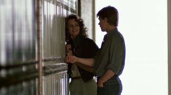 Movie still from “Footloose” (1984), directed by Herbert Ross – A man and a woman standing next to each other near a window; Medium shot, Low angle