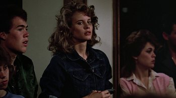 Movie still from “Footloose” (1984), directed by Herbert Ross – A young woman with long curly hair holding a cell phone; Close Up shot, Over the shoulder angle