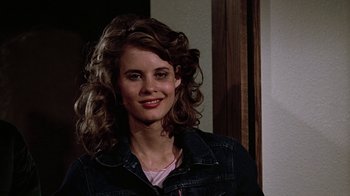 Movie still from “Footloose” (1984), directed by Herbert Ross – A young woman with long curly brown hair smiles for the camera; Close Up shot, Over the shoulder angle