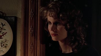Movie still from “Footloose” (1984), directed by Herbert Ross – A woman with curly brown hair is standing in front of a wooden door; Close Up shot, Low angle