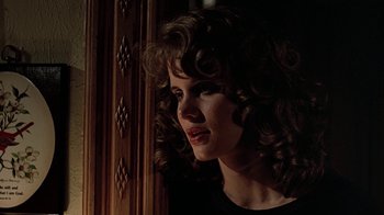 Movie still from “Footloose” (1984), directed by Herbert Ross – A woman with curly brown hair looking out of a window; Close Up shot, Over the shoulder angle