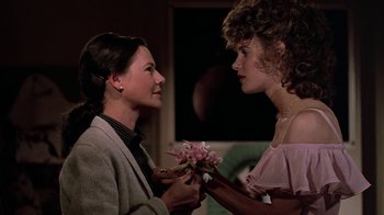 Movie still from “Footloose” (1984), directed by Herbert Ross – A woman holding a bouquet of flowers next to another woman; Medium shot, Over the shoulder angle