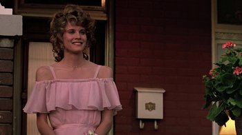 Movie still from “Footloose” (1984), directed by Herbert Ross – A woman in a pink dress standing in front of a brick wall; Medium shot, Low angle
