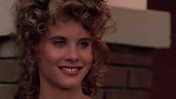 Movie still from “Footloose” (1984), directed by Herbert Ross – A person with curly hair smiling; Close Up shot, Over the shoulder angle
