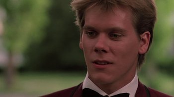 Movie still from “Footloose” (1984), directed by Herbert Ross – A man in a suit and bow tie looking to his left; Close Up shot, Over the shoulder angle