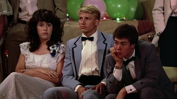 Movie still from “Footloose” (1984), directed by Herbert Ross – A group of young people sitting next to each other at a party; Medium shot, Low angle