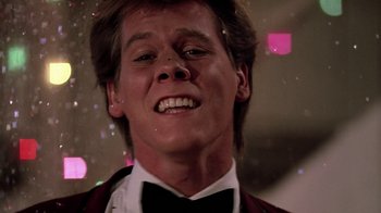 Movie still from “Footloose” (1984), directed by Herbert Ross – A person wearing a suit and bow tie; Close Up shot, Low angle