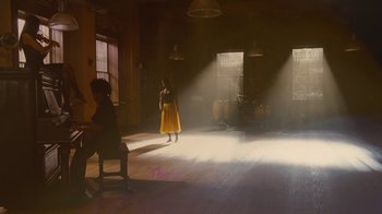 Movie still from “For Colored Girls” (2010), directed by Tyler Perry – A woman in a yellow dress standing in a dimly - lit room; Extreme Wide shot, Low angle