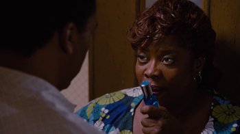 Movie still from “For Colored Girls” (2010), directed by Tyler Perry – A woman is holding a small device up to her mouth; Close Up shot, High angle