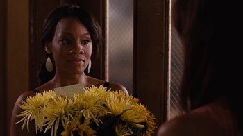 Movie still from “For Colored Girls” (2010), directed by Tyler Perry – A woman holding a bouquet of flowers in front of a mirror; Close Up shot, Over the shoulder angle