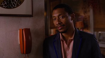Movie still from “For Colored Girls” (2010), directed by Tyler Perry – A man standing in front of a wall next to a phone; Close Up shot, Over the shoulder angle