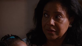 Movie still from “For Colored Girls” (2010), directed by Tyler Perry – An older woman looking at the camera while holding a baby; Close Up shot, Over the shoulder angle
