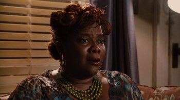 Movie still from “For Colored Girls” (2010), directed by Tyler Perry – An older woman wearing a green necklace and a floral dress; Close Up shot, Over the shoulder angle