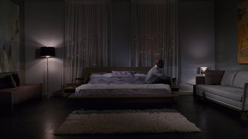 Movie still from “For Colored Girls” (2010), directed by Tyler Perry – A man sitting on top of a bed in a bedroom; Wide shot, High angle