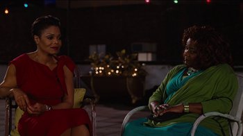 Movie still from “For Colored Girls” (2010), directed by Tyler Perry – Two women are sitting in a chair and one is holding a cell phone; Medium shot, Over the shoulder angle