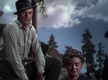 Movie still from “For Whom the Bell Tolls” (1943), directed by Sam Wood – A man and a woman sitting next to each other on the ground; Medium shot, Low angle