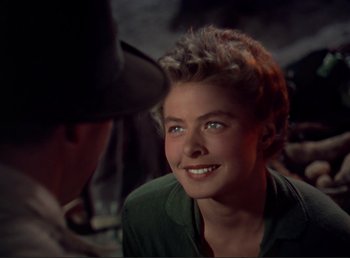 Movie still from “For Whom the Bell Tolls” (1943), directed by Sam Wood – A young woman smiling while a man is talking to her; Close Up shot, Over the shoulder angle