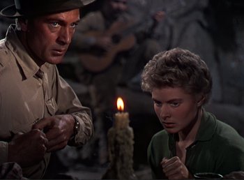 Movie still from “For Whom the Bell Tolls” (1943), directed by Sam Wood – A man and a woman standing in front of a candle; Medium shot, Low angle